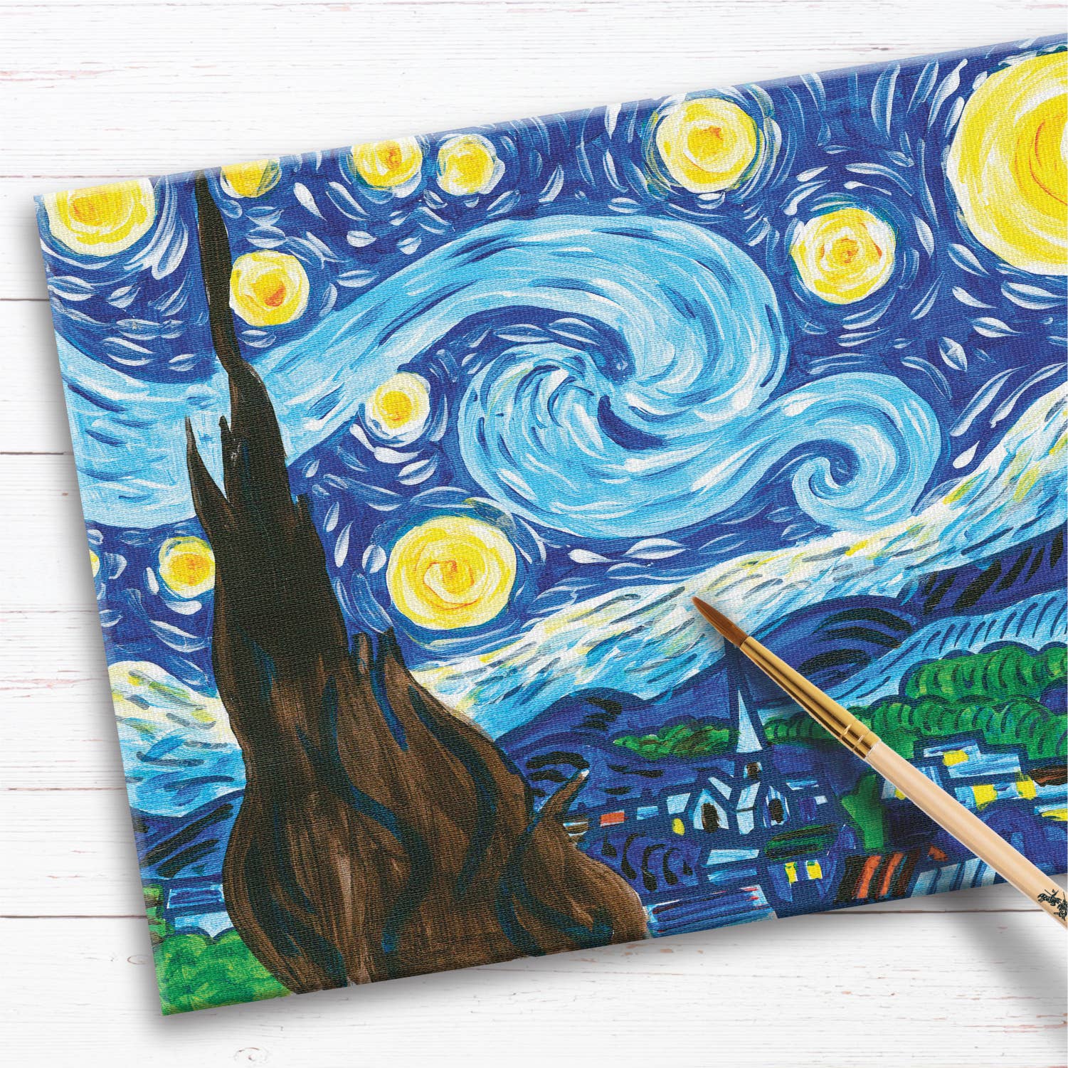 A partially painted canvas from the Paint by Number Museum Series - The Starry Night by Faber-Castell / Creativity for Kids rests on a white wooden surface, with a paintbrush laying along the right edge—an ideal kit for any beginner artist eager to recreate this iconic masterpiece.
