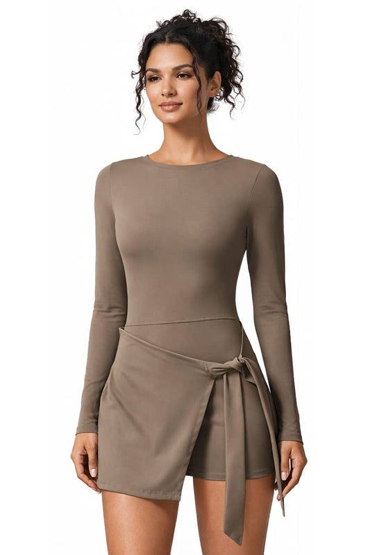 A woman wearing the Color 5 Mocha Long Sleeve Athletic Dress, featuring a round neckline and a wrap-style skirt tied at the waist, stands against a white background.