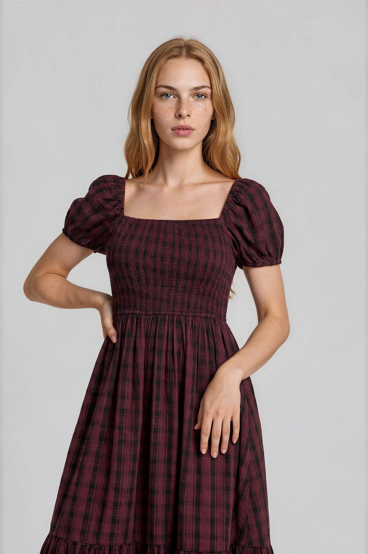 A person wears a Blu Pepper Burgundy Plaid Midi Dress in burgundy and black plaid with a square neckline and puffed short sleeves.