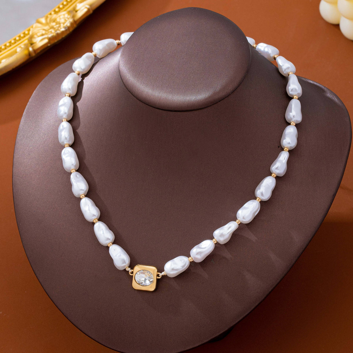 JOSSLYN by wall to wall Baroque Pearl & Bezel-Set Crystal Necklace featuring a strand of white baroque pearls alternating with small gold beads and a central square pendant with a bezel-set clear crystal.