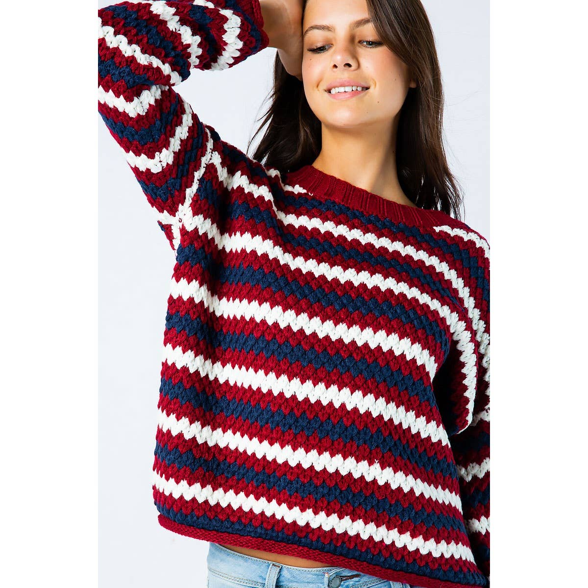 A woman wears a Sweet Generis Chunky Knit Multi Color Sweater featuring horizontal stripes in red, navy, and white.
