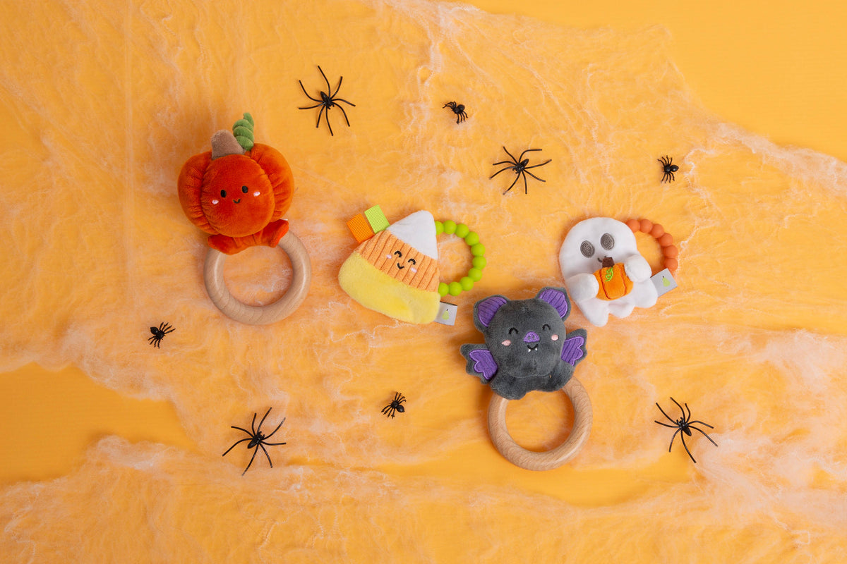 Pearhead Pumpkin Baby Wooden Teether Toy, Halloween and Fall featuring pumpkin, candy corn, bat, and ghost shapes on a yellow background with decorative cobwebs and toy spiders.