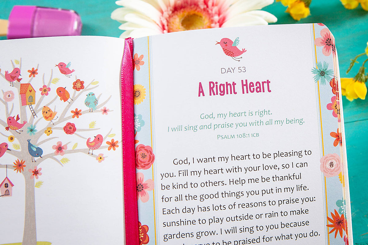 The 2-Minute Prayers for Girls Book by BroadStreet Publishing Group, LLC is open to Day 53: A Right Heart, featuring a Bible verse, prayer, and vibrant bird and flower illustrations. A pink pen and fresh flowers are placed in the background.