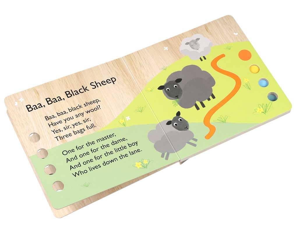 An open This Little Piggy Book by Simon & Schuster shows an illustrated nursery rhyme scene with several piglets on grassy hills and colored holes on the right page.