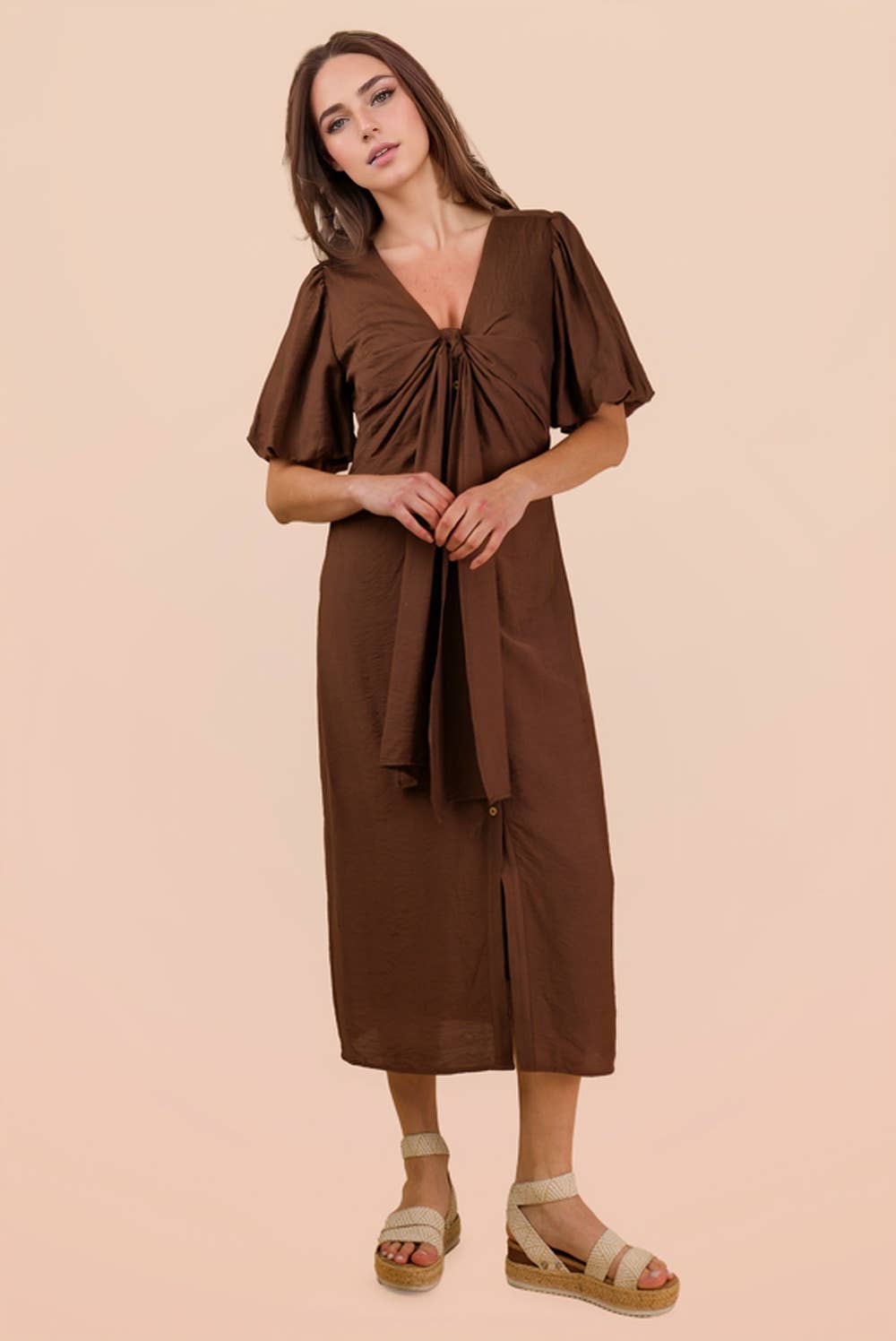 A woman wears a brown Mocha Front Tie Midi Dress by VERY J featuring puffed sleeves and a tie-front detail, paired with platform espadrille sandals.