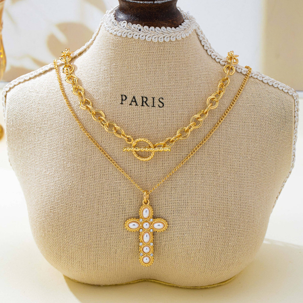 JOSSLYN by wall to wall Pearl Cross Layered Necklace Set featuring layered gold-tone chains with a toggle clasp and a cross pendant embellished with pearls and clear stones.