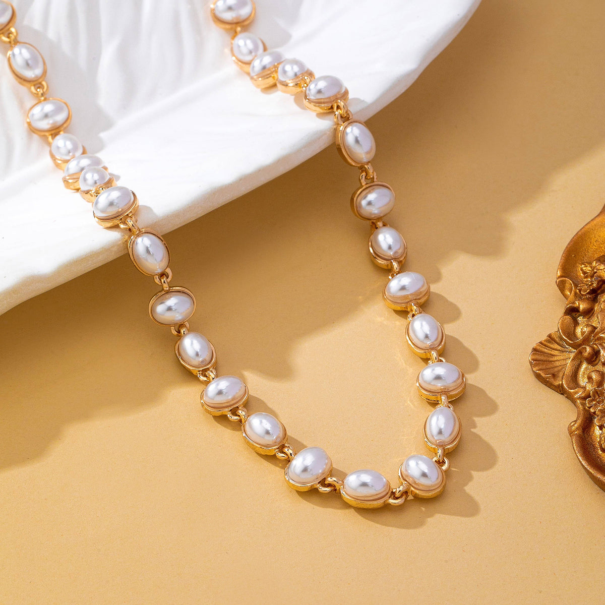 JOSSLYN by wall to wall Oval Pearl Link Necklace featuring a gold-toned chain with a series of oval-shaped white pearls set in metal links.