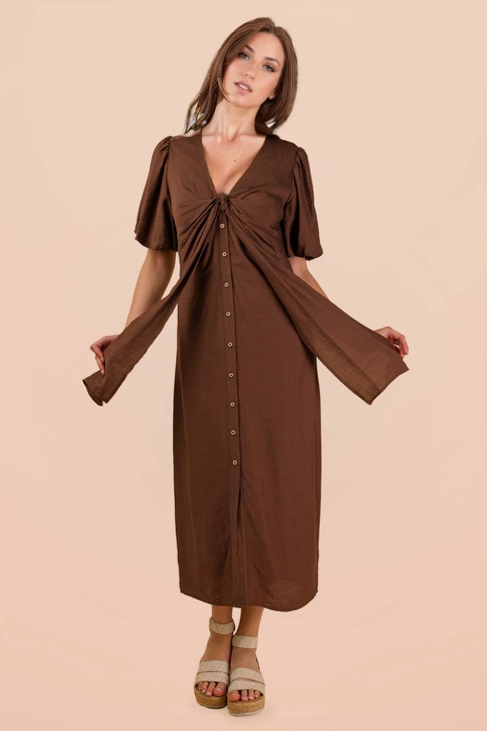 A woman wearing a mocha-colored VERY J Mocha Front Tie Midi Dress with a knotted bodice, front button closure, and espadrille sandals.