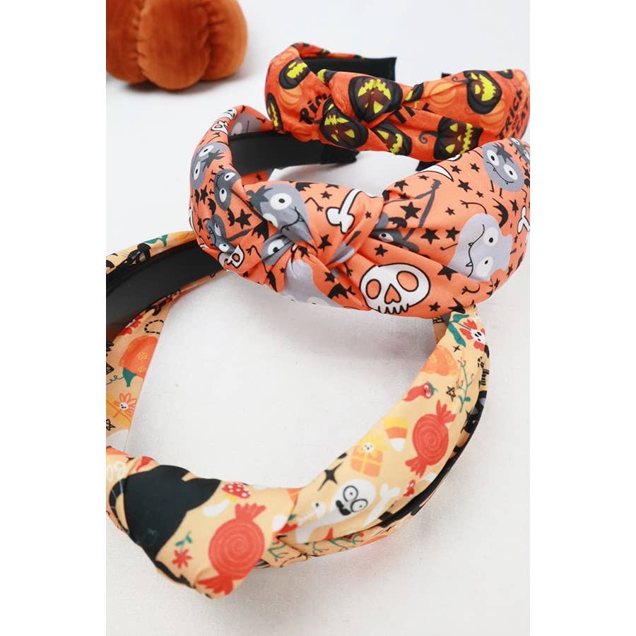 Two Love and Repeat Halloween Theme Headband knotted fabric headbands featuring orange and white patterns with ghosts, skulls, pumpkins, and candy.