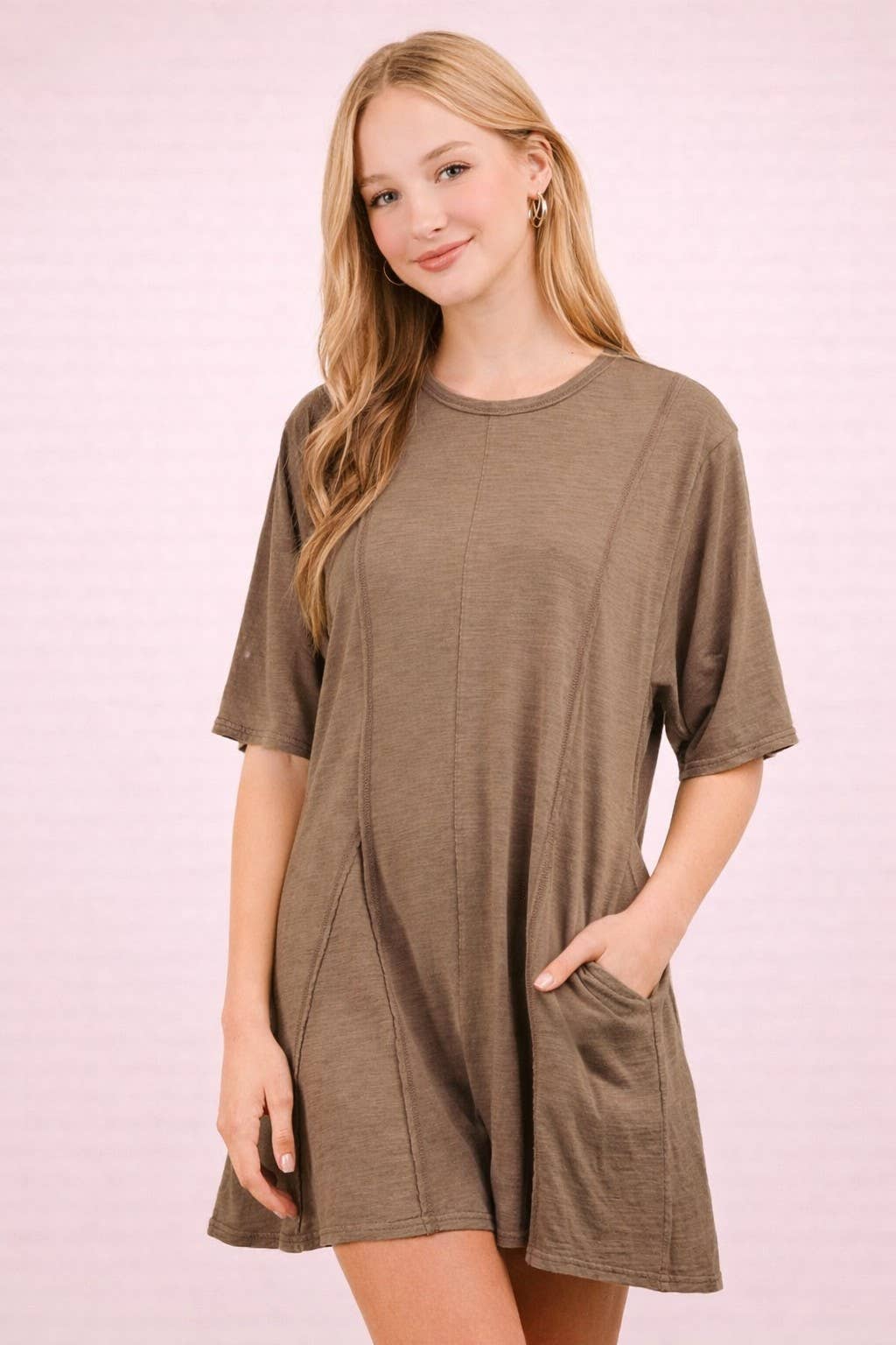 A woman wears a brown, short-sleeved Mineral Washed Oversized Romper by VERY J with side pockets.