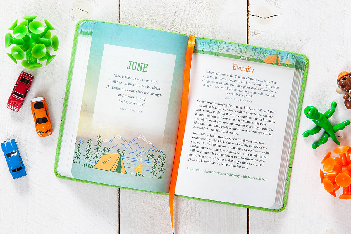 The A Daily Word for Boys Book by BroadStreet Publishing Group, LLC lies open on a white wooden surface, displaying June’s page with an illustrated tent and mountains, surrounded by small toy cars and green figures.