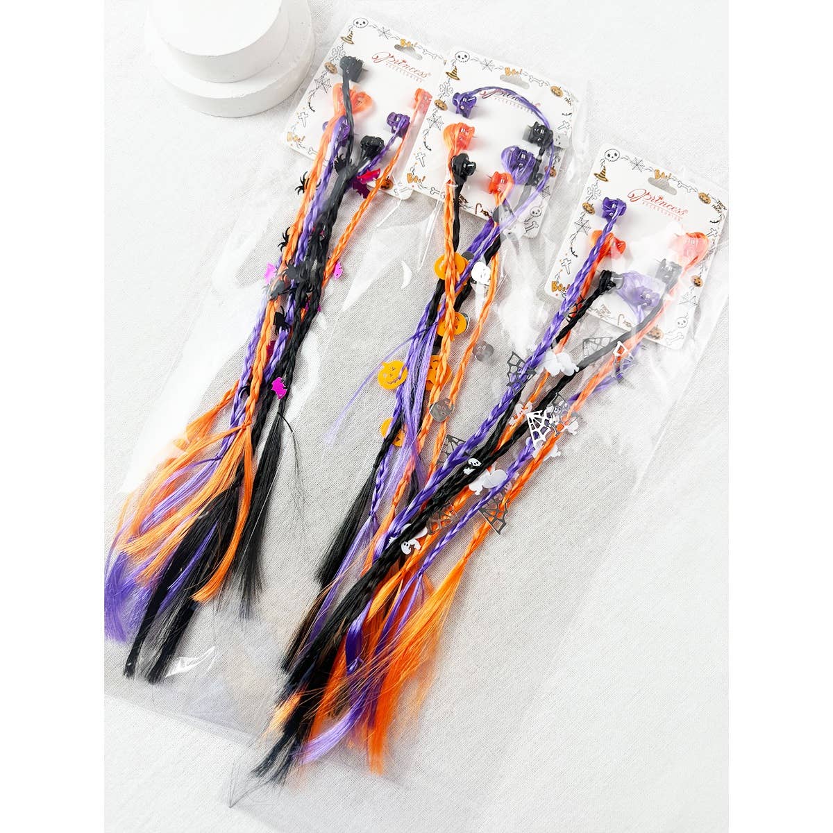 Love and Repeat Halloween Braid Hair Extension Clips featuring three sets of black, orange, and purple strands decorated with pumpkin, ghost, and spiderweb charms on display cards.