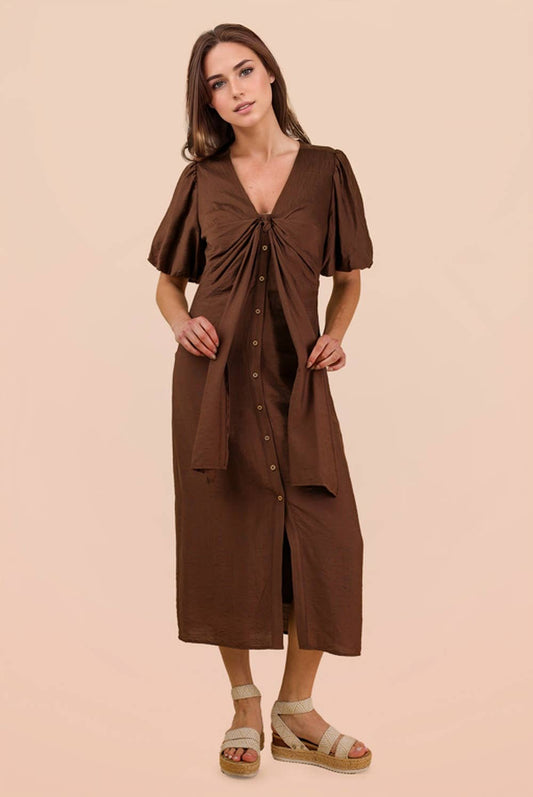A woman wears a brown VERY J Mocha Front Tie Midi Dress with short puff sleeves, a button-front closure, and a waist tie.