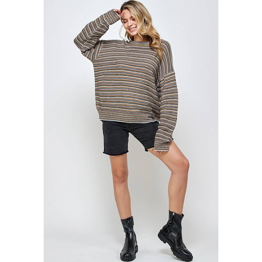A woman wearing a Sweet Generis Multi Color Stripe Pullover Sweater, black denim shorts, and black ankle boots.