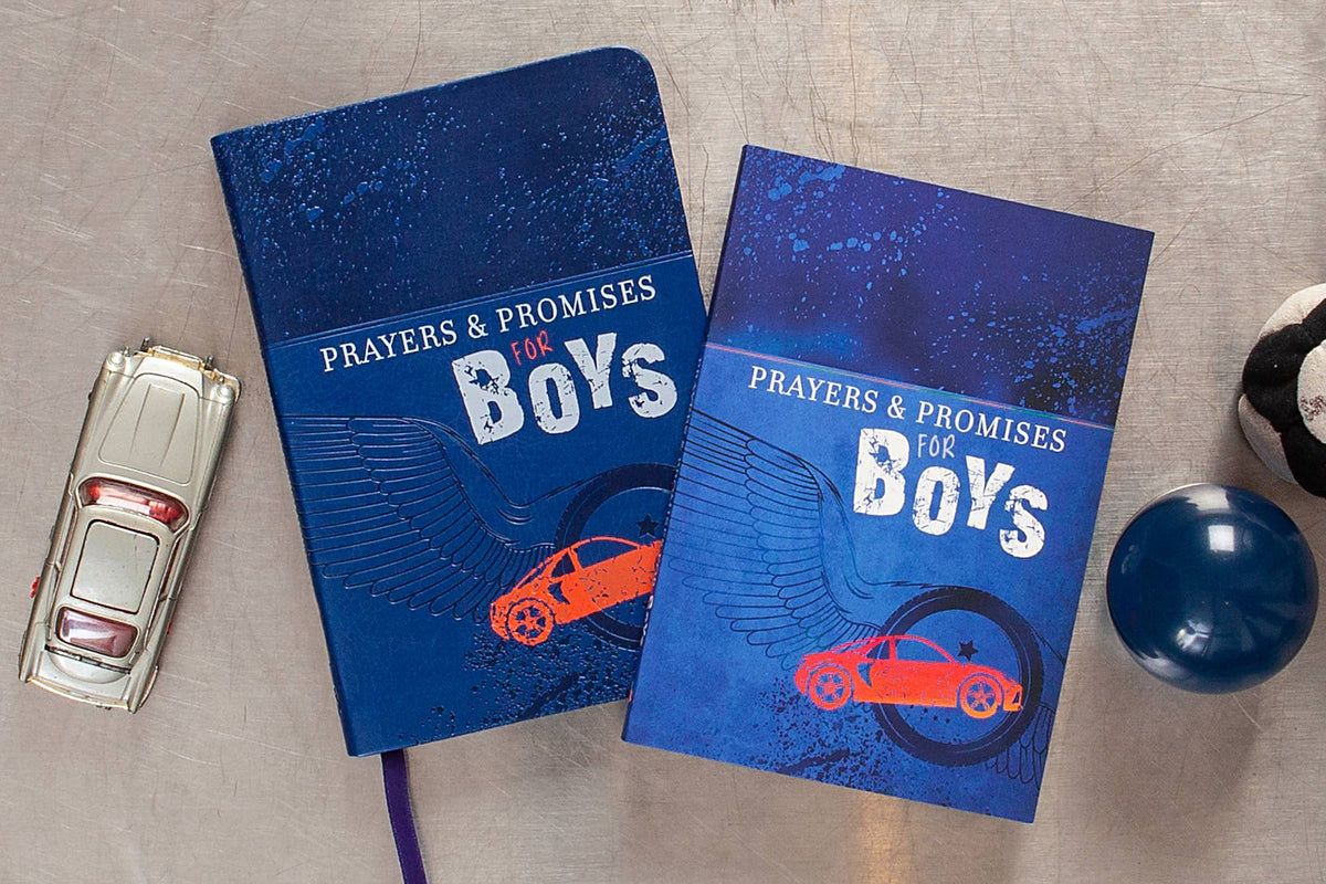 Two copies of Prayers & Promises for Boys Books by BroadStreet Publishing Group, LLC, featuring blue covers with orange cars, are on a table beside a toy car, a blue ball, and part of a black and white object.